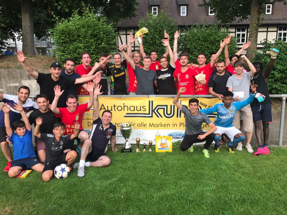 Große jubelnde Spielergruppe mit Pokalen hinter dem Autohaus-Kuhn-Banner